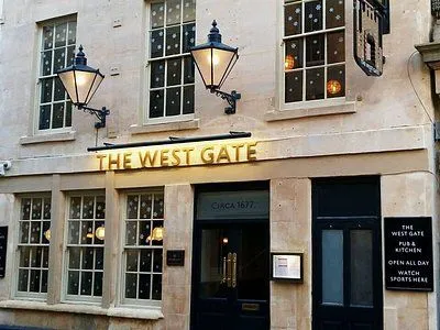 The image captures the exterior of a building, likely a pub or hotel named 'The West Gate'. It is well-lit, sharp, and highly photo-realistic, with natural colors. The key elements, such as the sign and entrance, are clearly in focus.