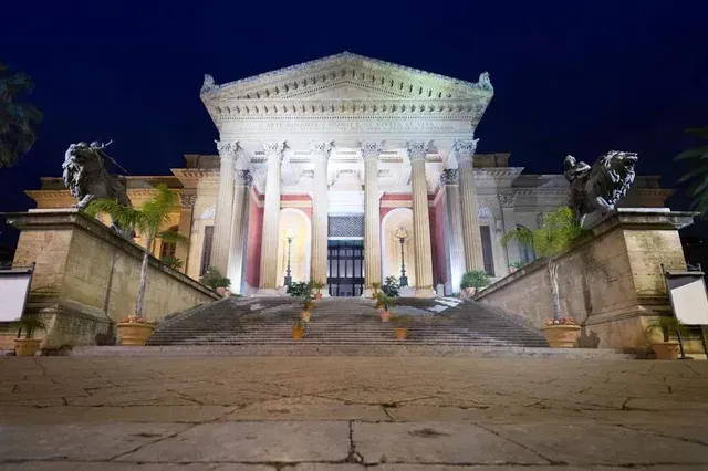 A well-composed and sharp image of a grand classical building at night. The artificial lighting effectively illuminates the structure, highlighting its architectural details. The deep blue night sky provides a good contrast.