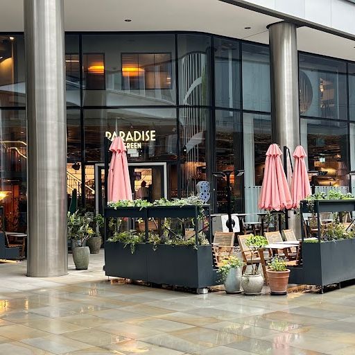 This image is an example of exterior photography. It shows a terrace with tables, chairs, and umbrellas. The terrace is located in front of a glass facade. The image is well-composed and well-lit. The colors are accurate, and the image is photo-realistic. All key elements are in focus. There are no unwanted elements. Score: 80 Strengths: - Well-composed and well-lit - Accurate colors - Photo-realistic - All key elements are in focus - No unwanted elements Weaknesses: - The image is a bit too centered and static