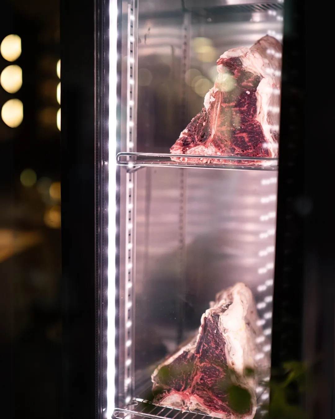 Dry-aged beef displayed in a professional refrigeration unit.