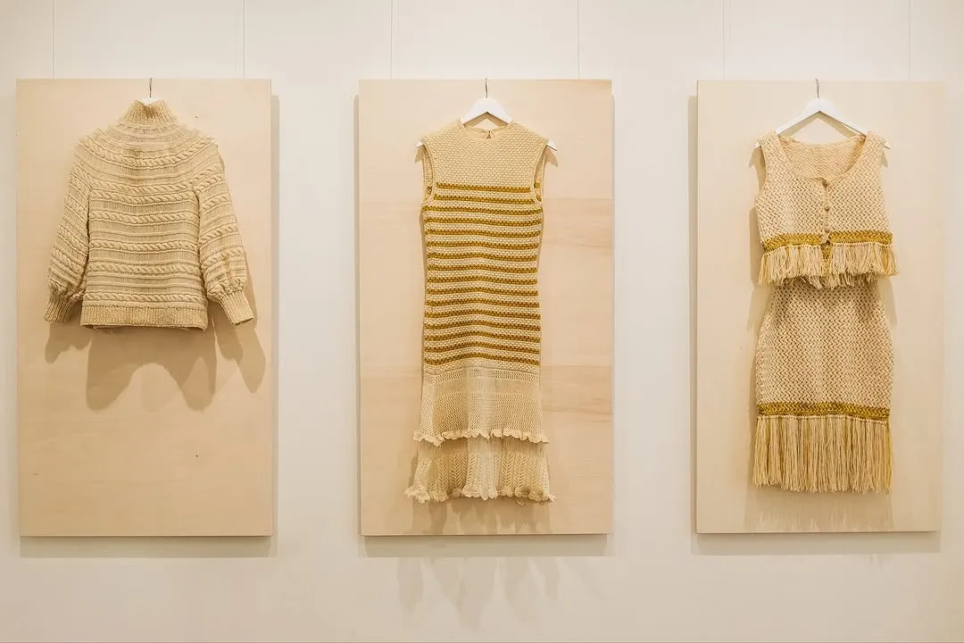 The image is well-composed, featuring a cream-colored knitted dress with yellow stripes prominently displayed. The lighting is excellent, ensuring the garment is evenly illuminated with accurate colors. The image is sharp, clearly showcasing the texture and details of the knitwear. All key elements are in focus, contributing to its strong photo-realistic quality.