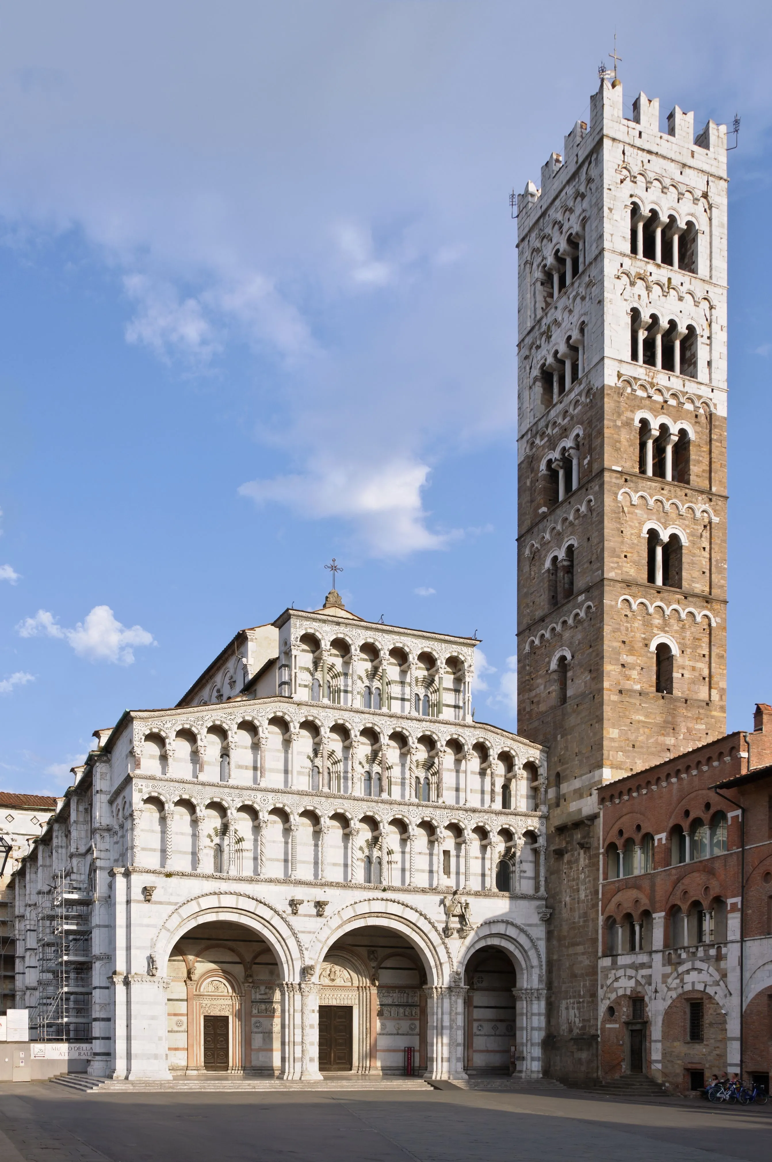 The image showcases a stunning cathedral and its bell tower under a clear sky. It demonstrates excellent sharpness, with all key architectural elements clearly in focus. The natural lighting is well-balanced, illuminating the facade and tower without harsh shadows or overexposure, enhancing the detailed stonework. The colors appear accurate and true to life, contributing to a highly photo-realistic representation. The composition is strong, capturing both structures effectively within the frame.
