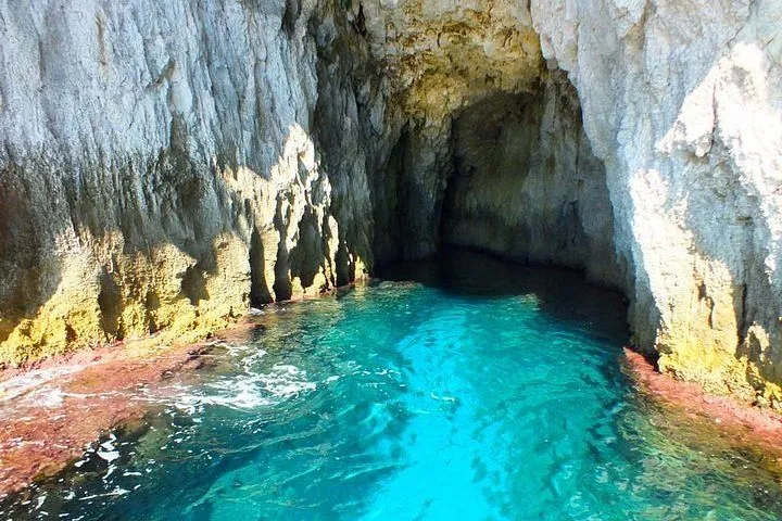 An editorial image capturing a sea cave with incredibly clear, vibrant turquoise water and textured rock walls.