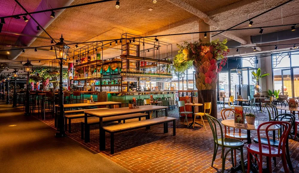 A well-composed and sharp photograph showcasing the interior of a vibrant restaurant or bar. The lighting is warm and inviting, highlighting the detailed bar area and various seating arrangements. Colors appear accurate, contributing to a lively ambiance. All key elements are in focus, and the image is highly photo-realistic.
