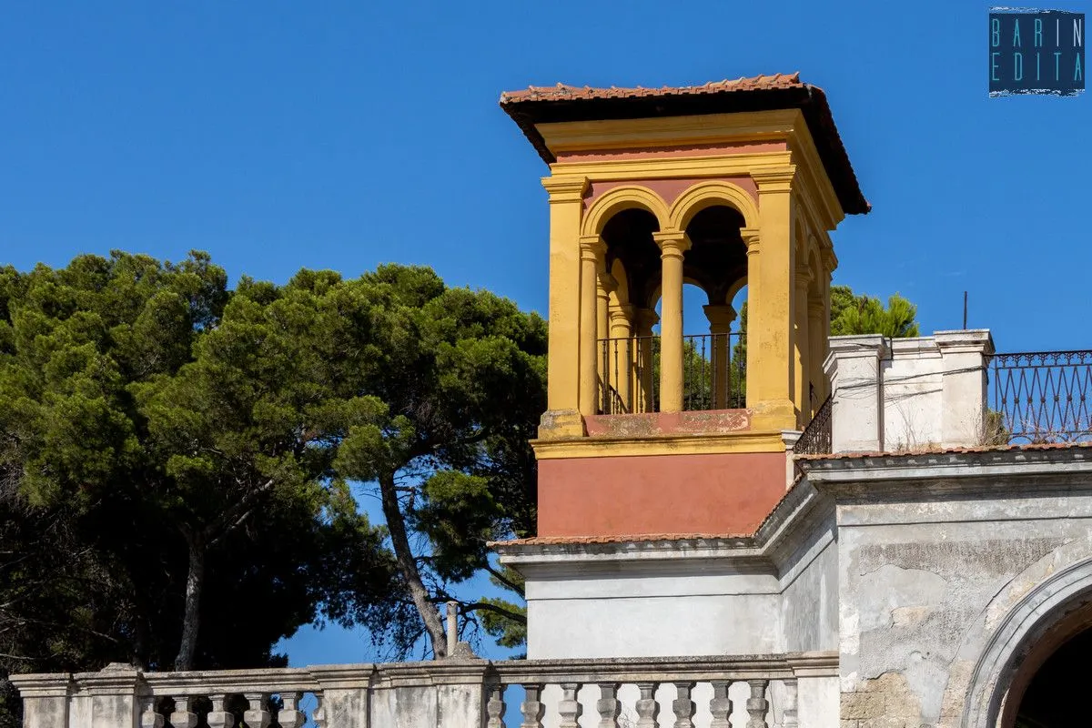 The image displays excellent overall quality with strong photo-realism, sharpness, and accurate colors under good natural lighting. The composition is well-balanced, featuring a historical tower, a lush tree, and a stone balustrade against a clear blue sky, with all key elements in sharp focus.