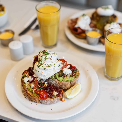 This image is a professionally taken close-up shot of a restaurant dish. The composition is excellent, highlighting the food attractively. The lighting is even and well-balanced, showcasing the colors and textures of the ingredients. The image is sharp, with good detail visible throughout. Colors appear accurate and the overall aesthetic is photorealistic. Key elements, such as the poached eggs and avocado toast, are perfectly in focus. No unwanted elements are present.