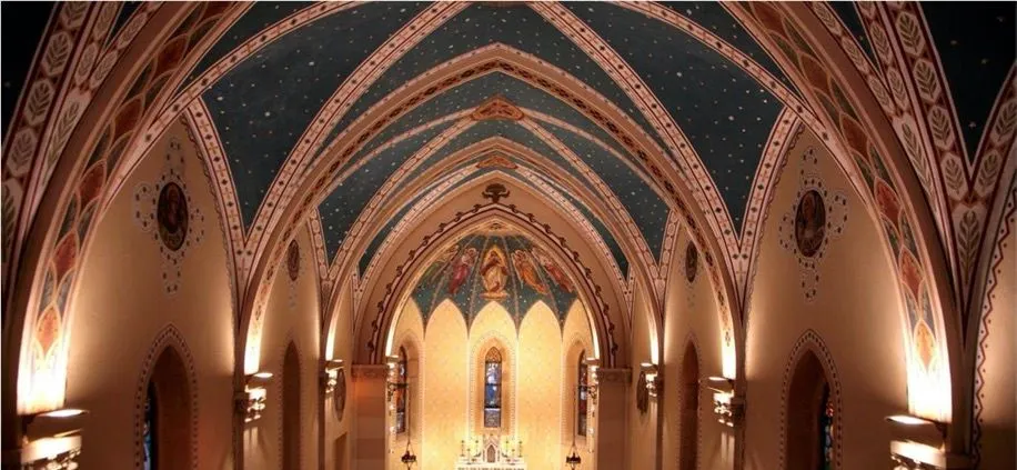 An interior shot of a church or cathedral, highlighting the vaulted ceiling with intricate patterns and murals above the altar.
