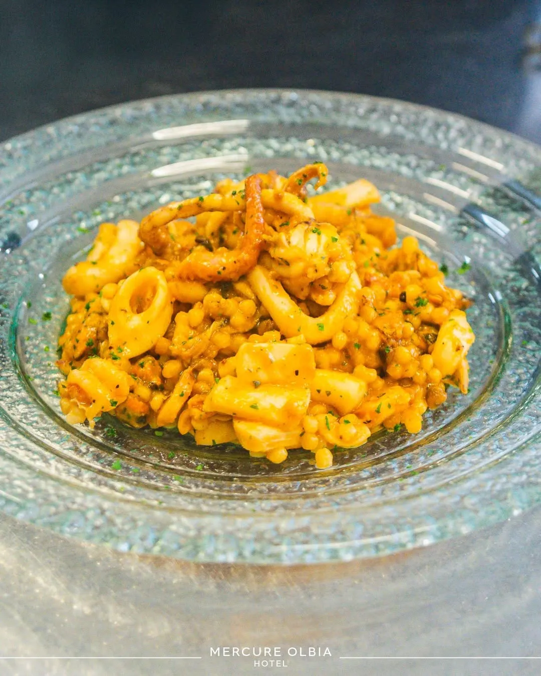 The image features a well-composed and sharp close-up of a seafood and pasta dish. The lighting is generally good, showcasing the food's natural colors. Key elements are in focus, contributing to a photo-realistic appearance. The background, however, contains some reflections on the plate which slightly distract from the main subject.