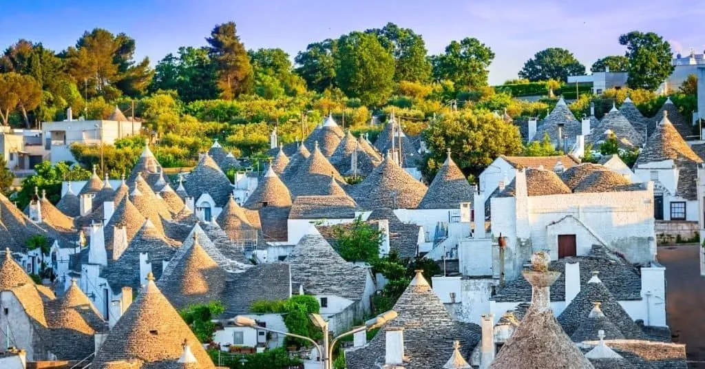An aerial view showcasing the unique Trulli houses with their distinctive conical stone roofs in a sunlit village setting.