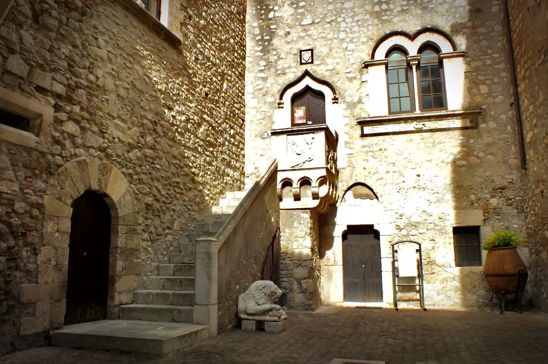 The image is well-composed, effectively showcasing the architectural details of the old stone building, including the staircase, ornate balcony, and lion statue. Key elements are sharp and in focus, contributing to its photo-realistic quality. However, the image suffers from harsh lighting, which results in strong shadows and blown-out highlights, diminishing overall detail and dynamic range. The color accuracy could also be improved, as the image has a slightly desaturated and warm cast.
