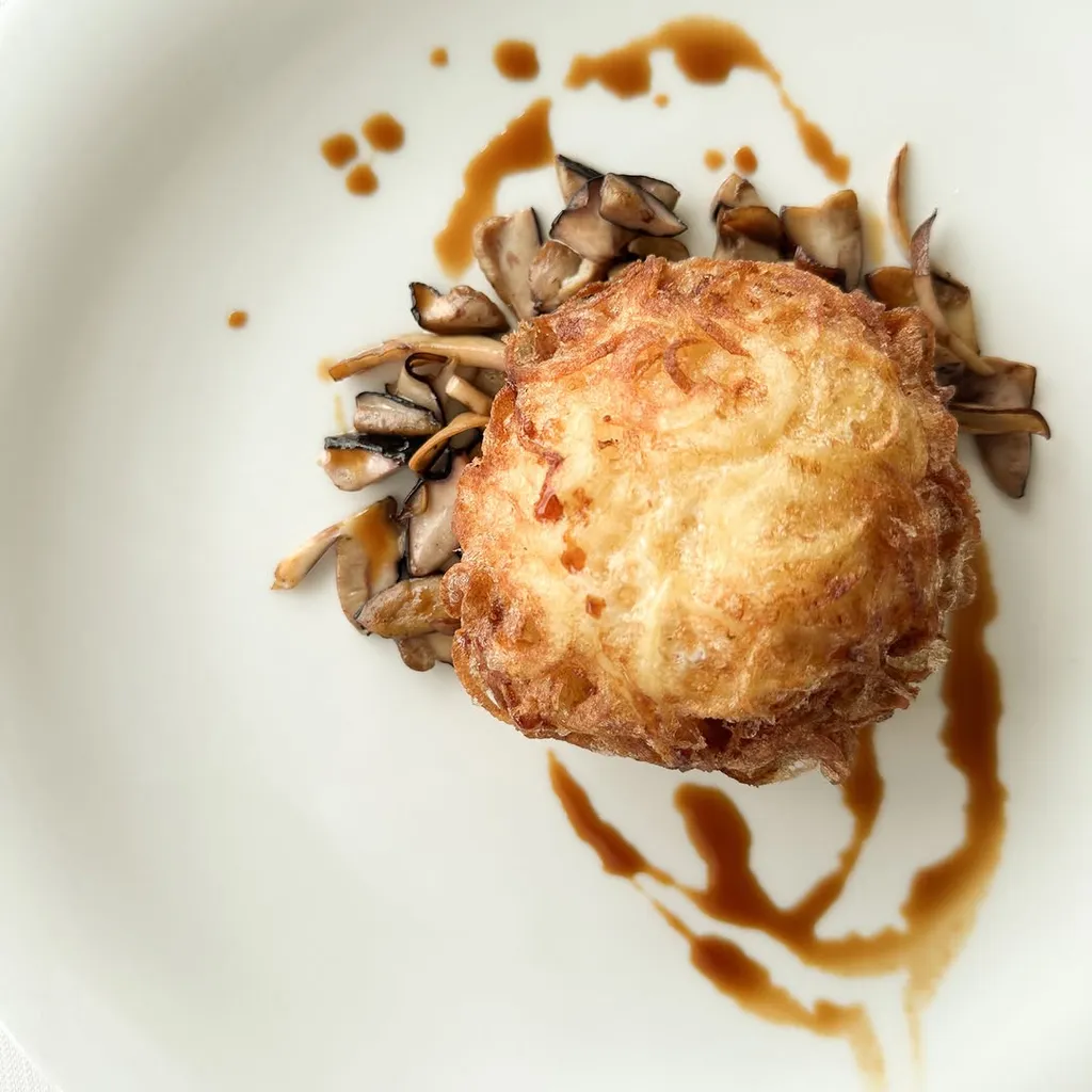 The image is very well-composed, featuring the dish elegantly centered on a pristine white plate, enhancing its visual appeal. The lighting is excellent, providing an appetizing look and highlighting the textures of the food. All key elements are sharp and in focus, contributing to a highly photo-realistic and color-accurate representation of the dish.