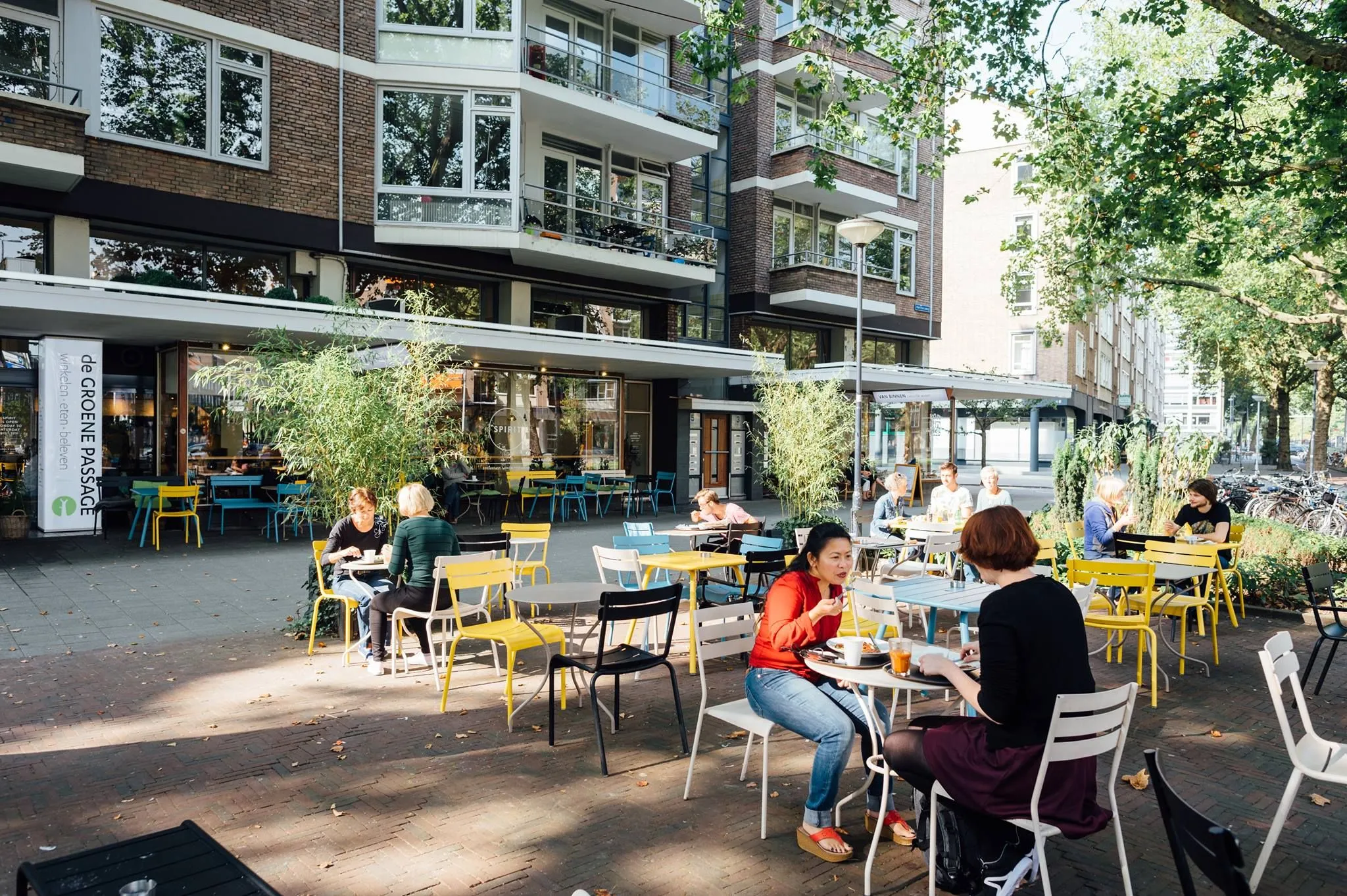 The image captures a lively outdoor cafe scene with good overall composition, natural lighting, and realistic colors. Key subjects in the foreground are sharp and in focus, contributing to its photo-realistic quality. While some areas show minor fall-off in sharpness towards the background and slight variations in lighting, these do not significantly detract from the overall quality.