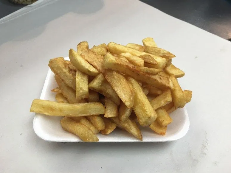 An image featuring a generous serving of golden-brown chips on a simple white tray. The lighting is even, and the colors appear natural. The chips in the foreground are sharp, making them the clear focus of the image.