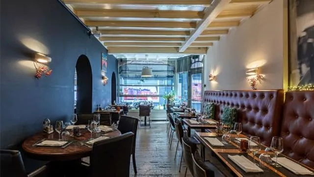 An inviting view into a contemporary restaurant interior, featuring neatly set tables, comfortable seating, and a distinct color palette.