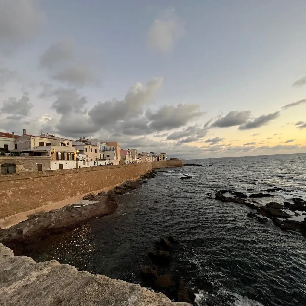 The image is well-composed, capturing a scenic coastal town at dusk or dawn with a strong sense of realism. Key elements such as the buildings and the wall along the coastline are sharp and in focus. The colors appear natural and accurate for the ambient light conditions.