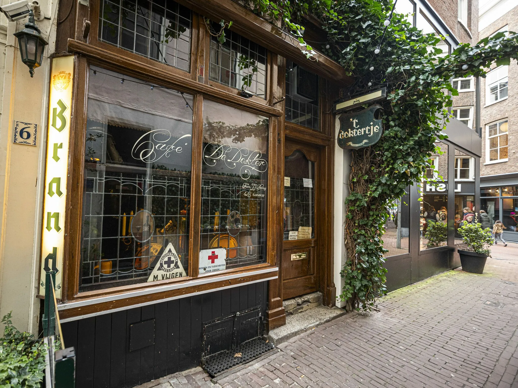 The image is a well-composed and sharp editorial-style photograph of a charming cafe or bar exterior. The colors are natural, and key elements like the wooden facade, windows, and ivy are in clear focus. While the lighting is somewhat flat, resulting in noticeable reflections on the windows, it does not significantly detract from the overall quality.
