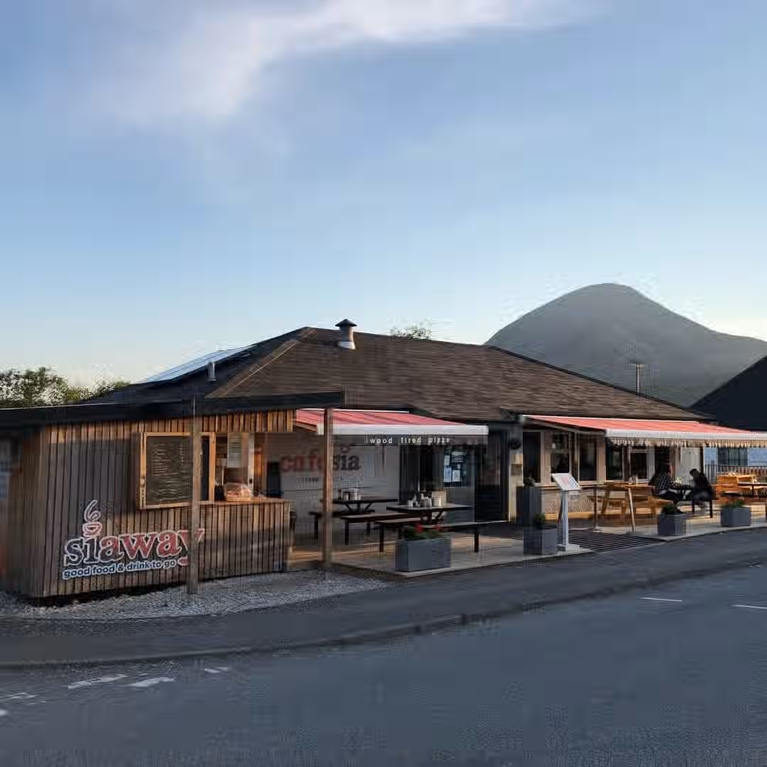 The image shows the exterior of a cafe with a mountain in the background. The composition is decent, though not particularly striking. The lighting is good, appearing to be natural daylight. Sharpness is acceptable, but could be improved. Colors appear accurate. The image is reasonably photo-realistic. Key elements, such as the cafe signage, are generally in focus. The image is not cluttered and does not contain any unwanted elements. The composition could be improved to highlight the cafe more effectively against the backdrop of the mountain.