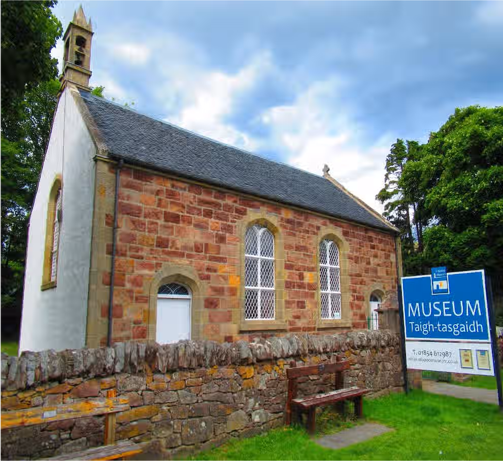 The image shows the exterior of a museum building. The composition is decent, with the building and signage clearly visible. The lighting is acceptable, though slightly overcast. Sharpness is good, allowing for detail in the stonework and architectural features to be seen. Color accuracy appears fine. The image is reasonably photo-realistic. Key elements like the building facade and museum sign are in focus. The composition could be improved to better highlight the building's architectural details. The image is not cluttered and contains no unwanted elements.
