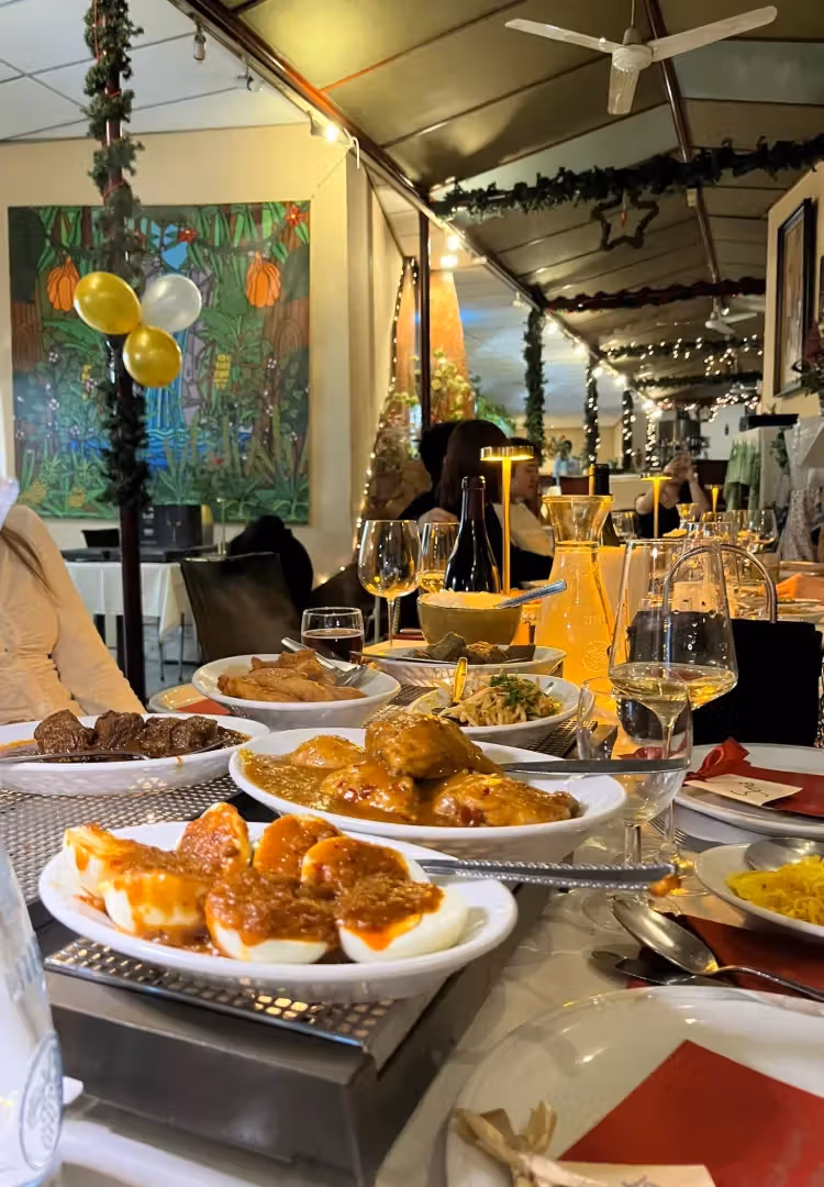 The image contains a table laden with food, drinks, and cutlery, suggesting a restaurant setting or a festive dinner. However, the image quality is poor. The composition is cluttered, and the lighting is not ideal, resulting in a lack of sharpness. The focus is not well-defined, and the image appears somewhat blurry. The presence of cutlery on plates and the overall composition detract from the image's appeal. The image is not photo-realistic. The presence of multiple plates of food and drinks that aren't full are unwanted elements.