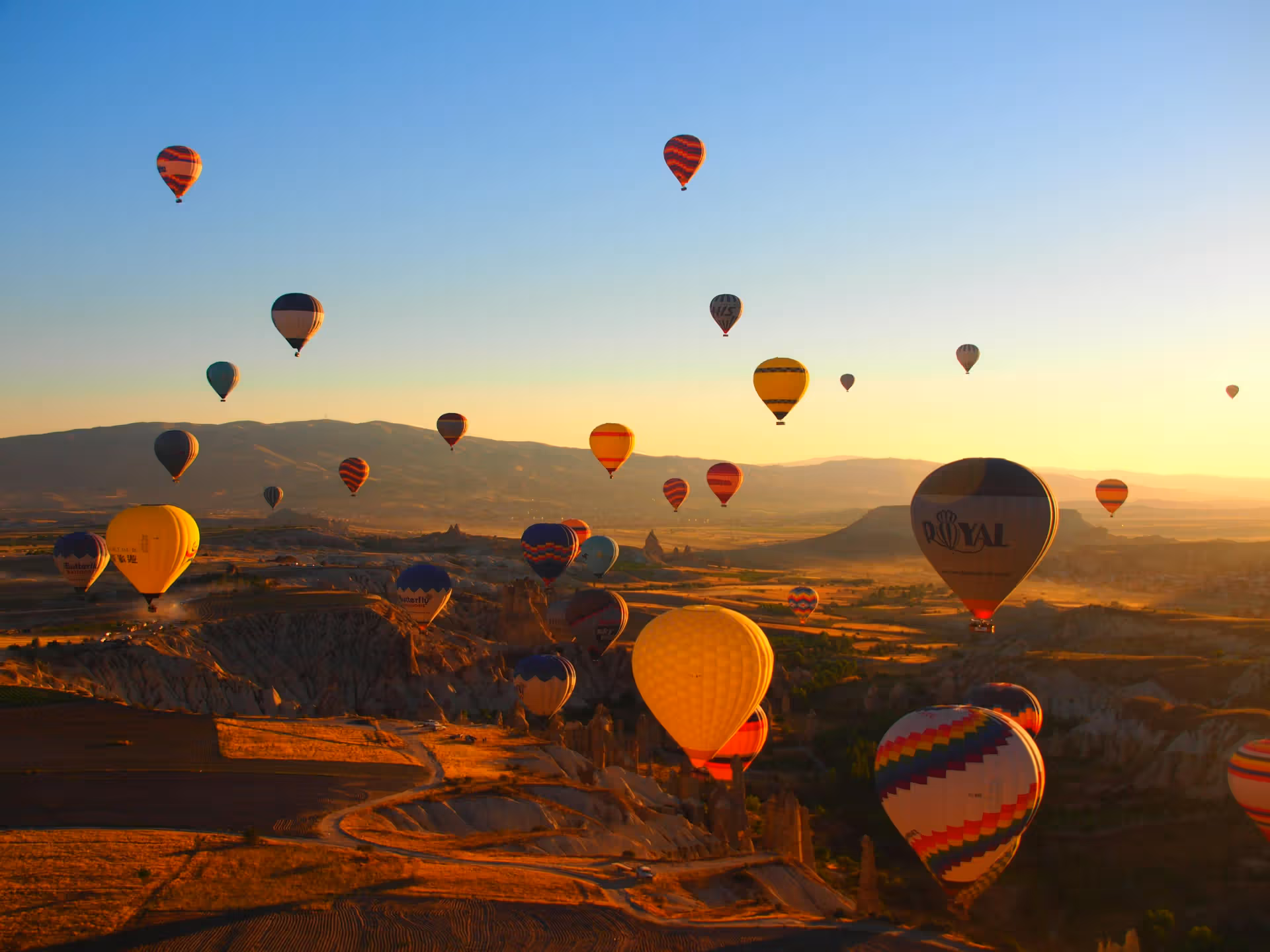 The image is well-composed, capturing a scenic landscape filled with hot air balloons at sunrise. The lighting is warm and inviting, enhancing the overall appeal. The image is sharp, and the colors are accurate, contributing to a photo-realistic feel. Key elements, such as the balloons, are in focus. The composition is strong, and the overall quality is high. It is a visually appealing image.