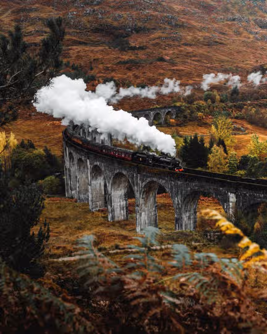 The image is well-composed, capturing a steam train on a viaduct in a scenic landscape. The lighting is good, creating a photo-realistic feel. The image is sharp, and the key elements, such as the train and the viaduct, are in focus. The colors appear accurate. Overall, it's a high-quality image with minor room for improvement in sharpness and focus across the entire scene.