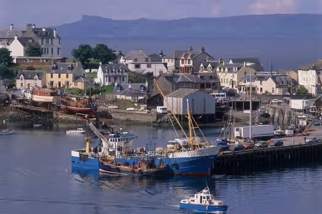 The image is well-composed, capturing a harbor scene with boats, buildings, and water. The lighting is adequate, though the colors appear slightly muted. The sharpness is acceptable, but not exceptional. The key elements, such as the boats and buildings, are in focus. Overall, the image is photo-realistic, but could benefit from improved color accuracy and sharpness. The composition is well balanced. The image does not contain any unwanted elements. The image is well-lit, and the key elements are in focus.
