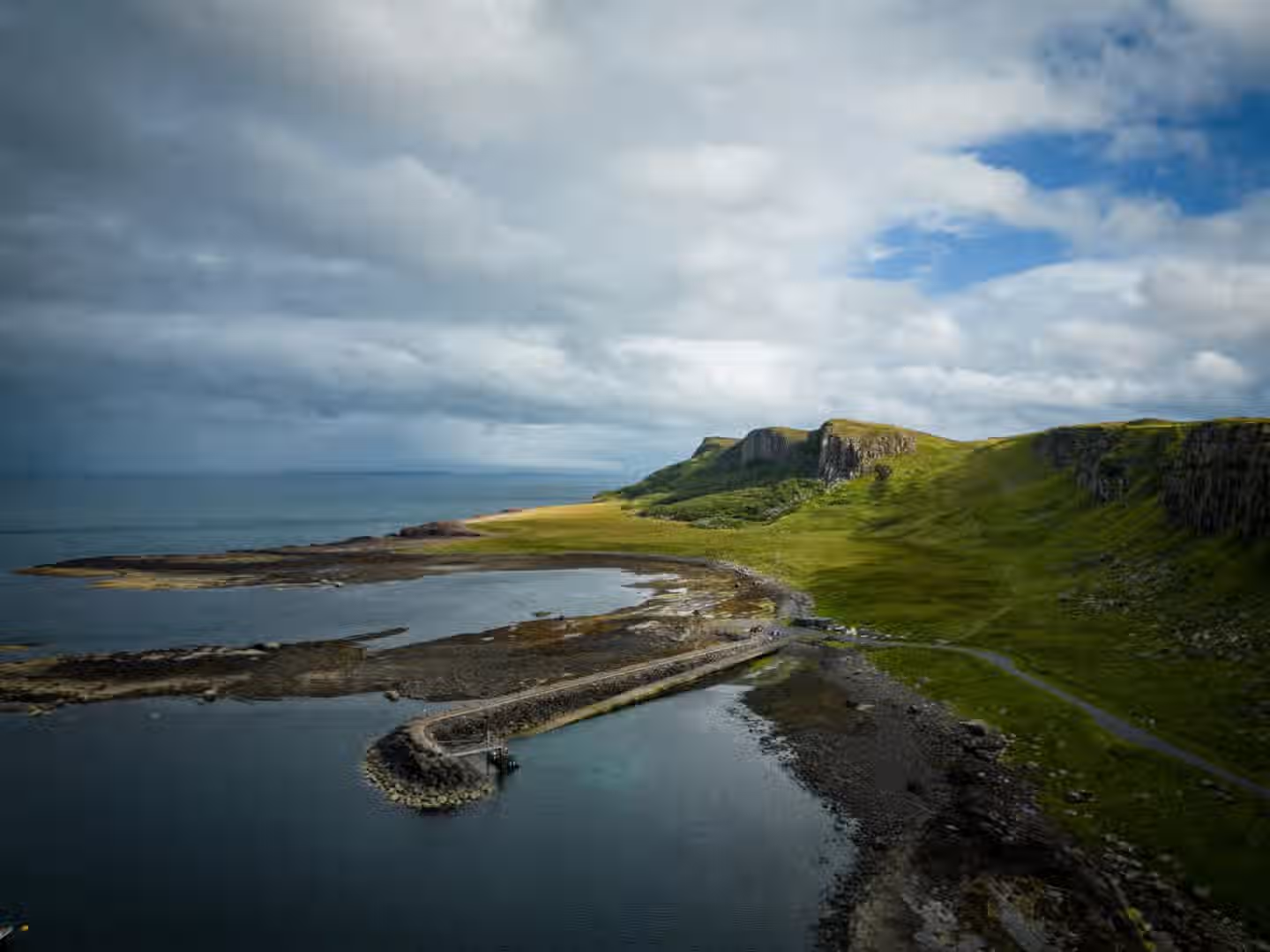 The image is well-composed with a clear focal point on the coastline and mountains. The lighting is good, with a mix of sunlight and cloud cover creating interesting shadows and highlights. The image is sharp and the colors are accurate. It appears photo-realistic. Key elements like the coastline and mountains are in focus. The image is well-composed, well-lit, sharp, and color-accurate. It is also photo-realistic and has key elements in focus. The composition is strong, drawing the eye through the scene. The lighting is dynamic, adding depth and interest. The sharpness is good, allowing for clear details. The colors are natural and accurate. Overall, it's a high-quality landscape photograph.