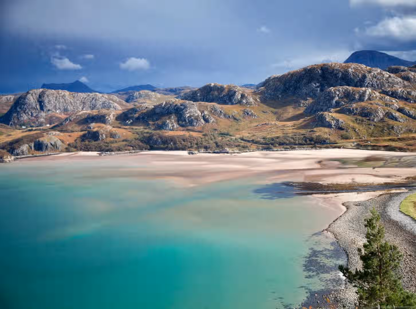 The image presents a well-composed coastal landscape featuring mountains, a beach, and turquoise water. The lighting is generally good, although there's some contrast between the brighter sky and the foreground. The sharpness is adequate, allowing for reasonable detail in the landscape. The colors appear accurate and vibrant, particularly the turquoise water. The image is photo-realistic. Key elements such as the mountains and the coastline are in focus. Overall, the image is aesthetically pleasing and meets the criteria well.