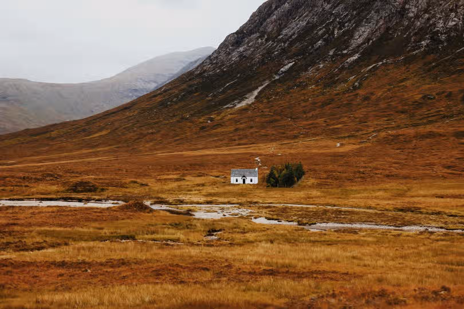 The image is well-composed with a clear focal point on the building. The lighting is soft and even, contributing to a pleasant overall aesthetic. The sharpness is good, and the colors are accurate, representing the natural tones of the landscape. The image appears photo-realistic. The key elements, such as the building and the surrounding landscape, are in focus. The image benefits from a balanced composition and natural color palette, creating a visually appealing scene. It could be improved with slightly enhanced sharpness to bring out more detail in the distant mountains.