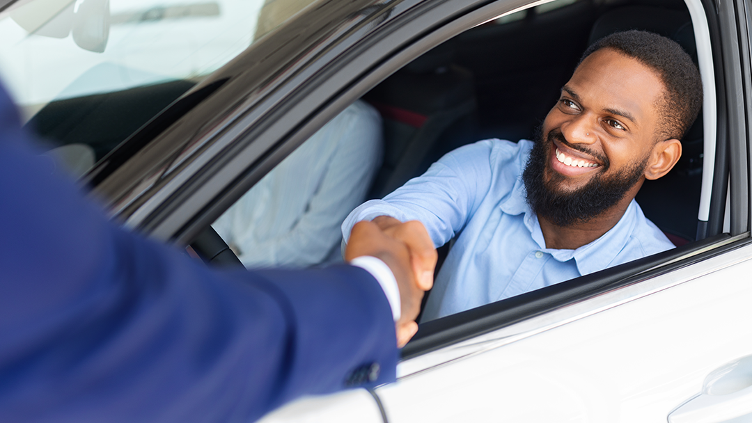 Vue d'un homme ayant acheté une nouvelle voiture et serrant la main du vendeur