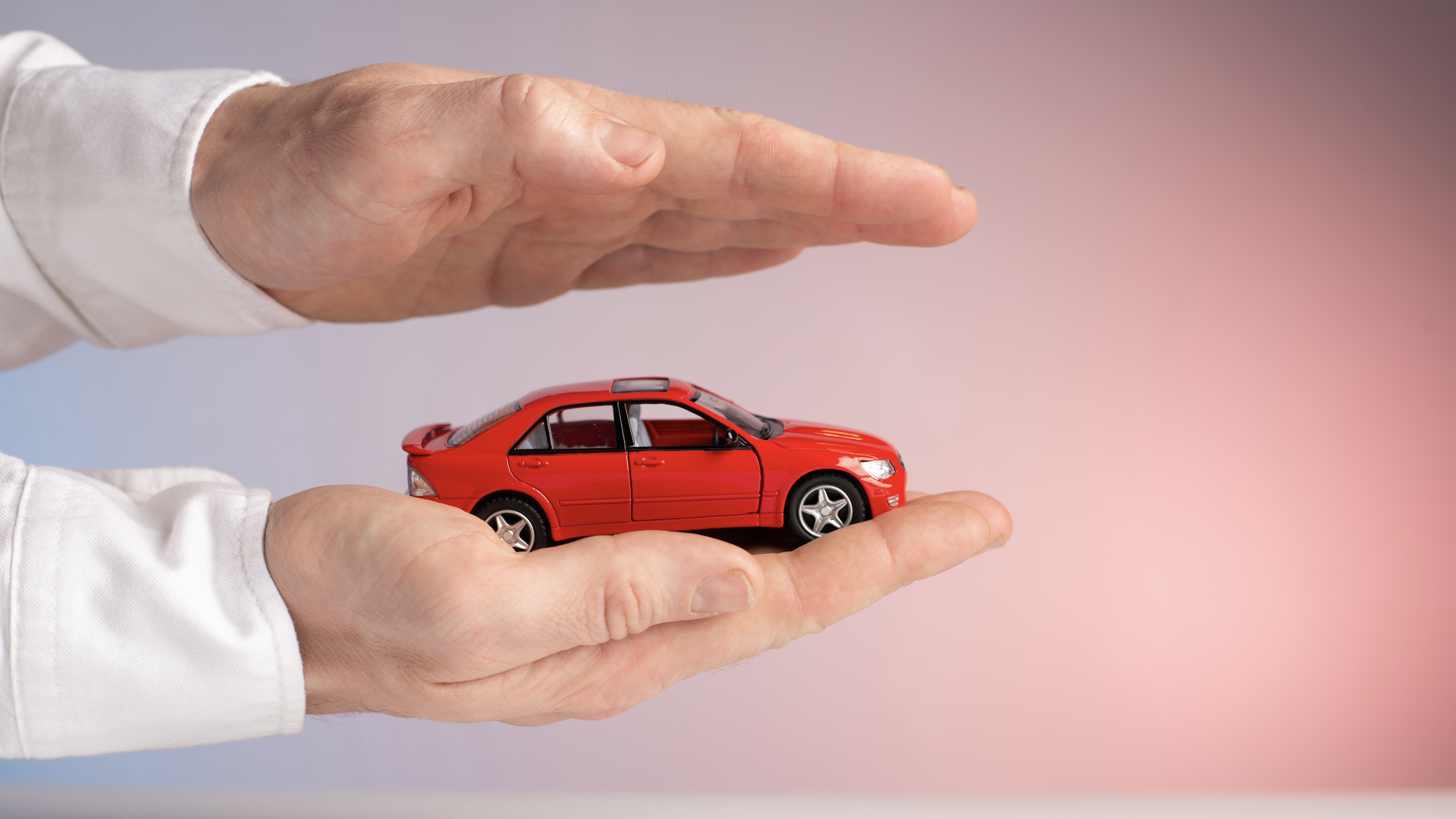 Une personne tient une petite voiture dans ses mains pour la protéger.