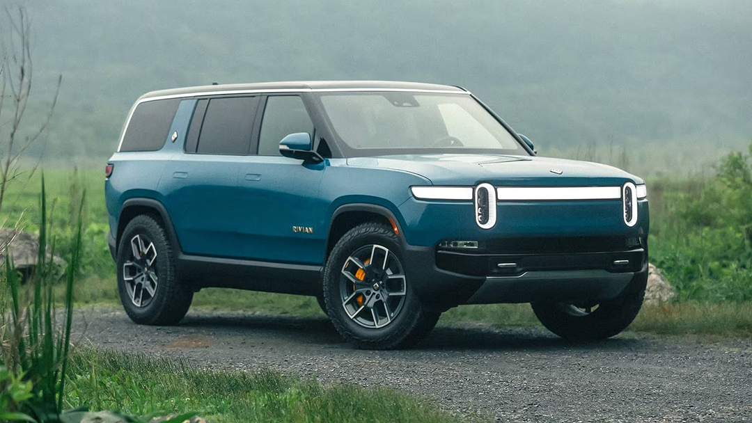 Vue 3/4 avant et latérale de la Rivian R1S 2022 sur route de terre un matin brumeux