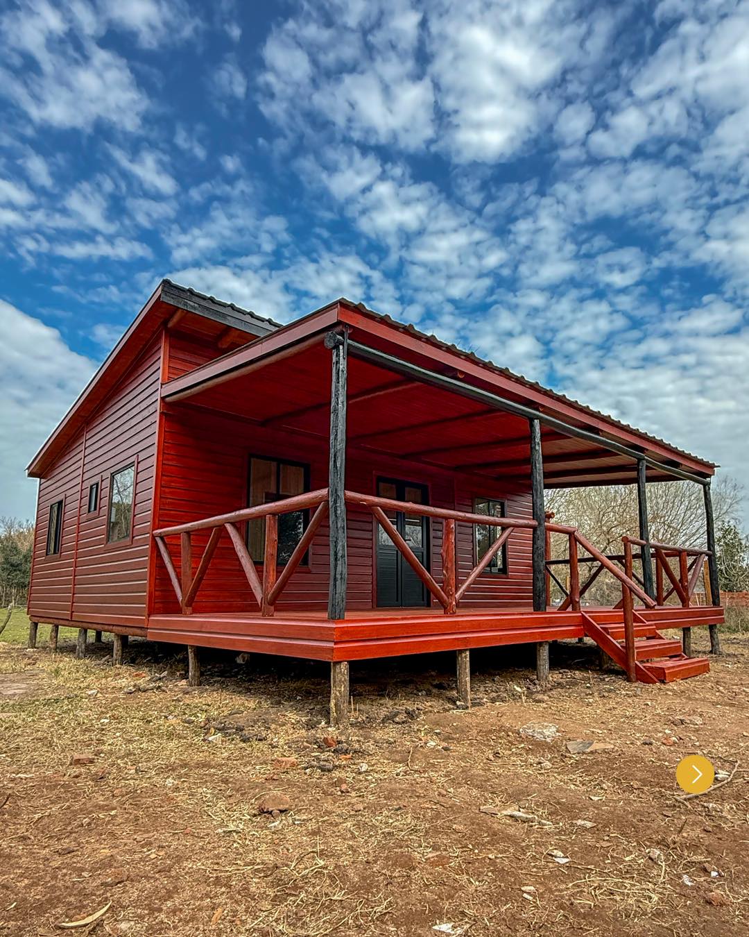 Cabaña de madera de dos pisos con balcón.