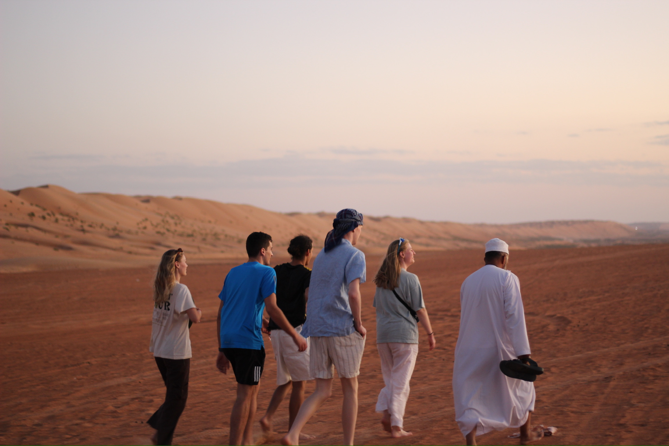 Travellers walking in the Omani desert at sunset