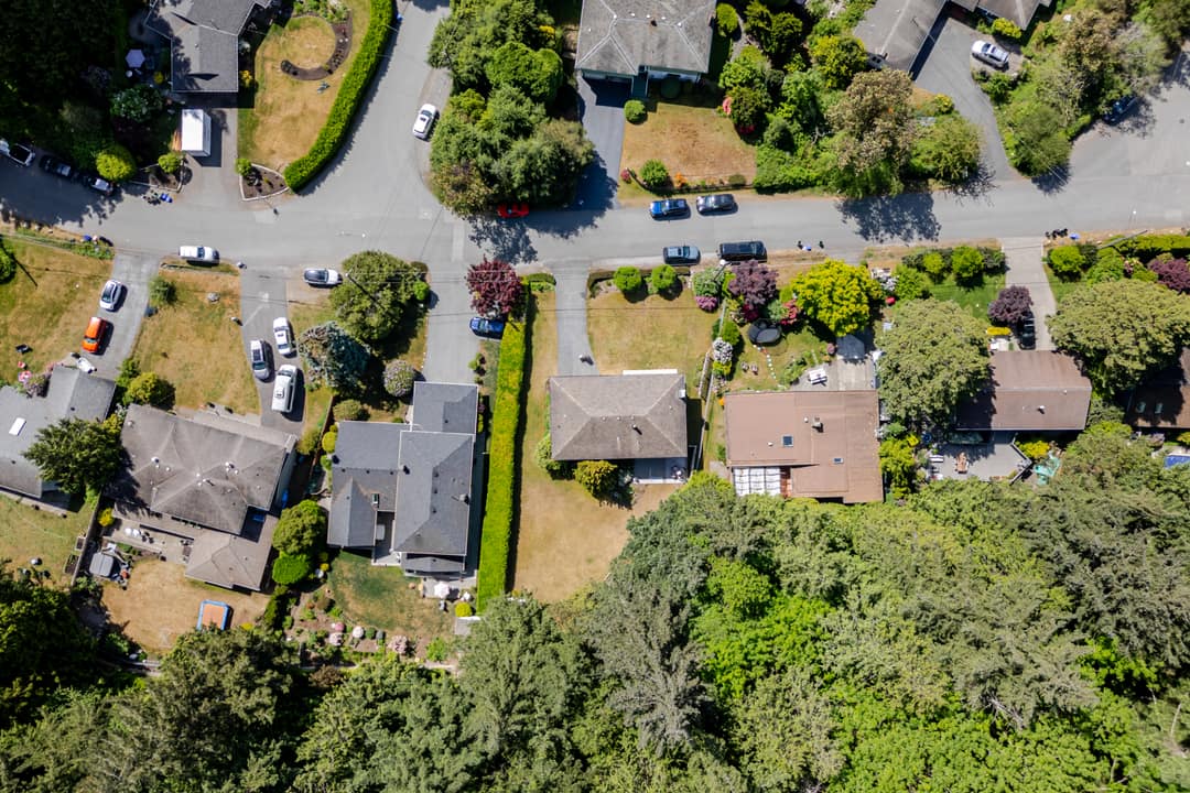 Straight-down aerial drone shot showing the roofline, lot size, hedged boundaries, and surrounding residential properties in Horseshoe Bay.