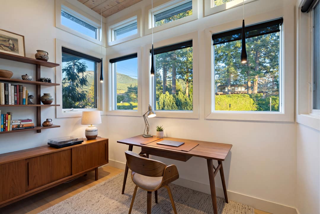A before-and-after interior design transformation of a home office in West Vancouver, transitioning from a cluttered workspace to a sleek West Coast Modern aesthetic with a walnut desk, minimalist shelving, and mid-century furnishings.