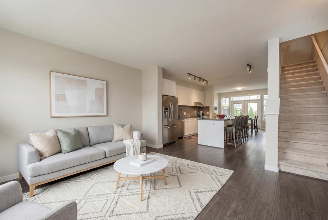 Before and after virtual restaging of a townhouse living room in Coquitlam, showing furniture replacement and AI photo enhancement with a brighter, modern aesthetic.