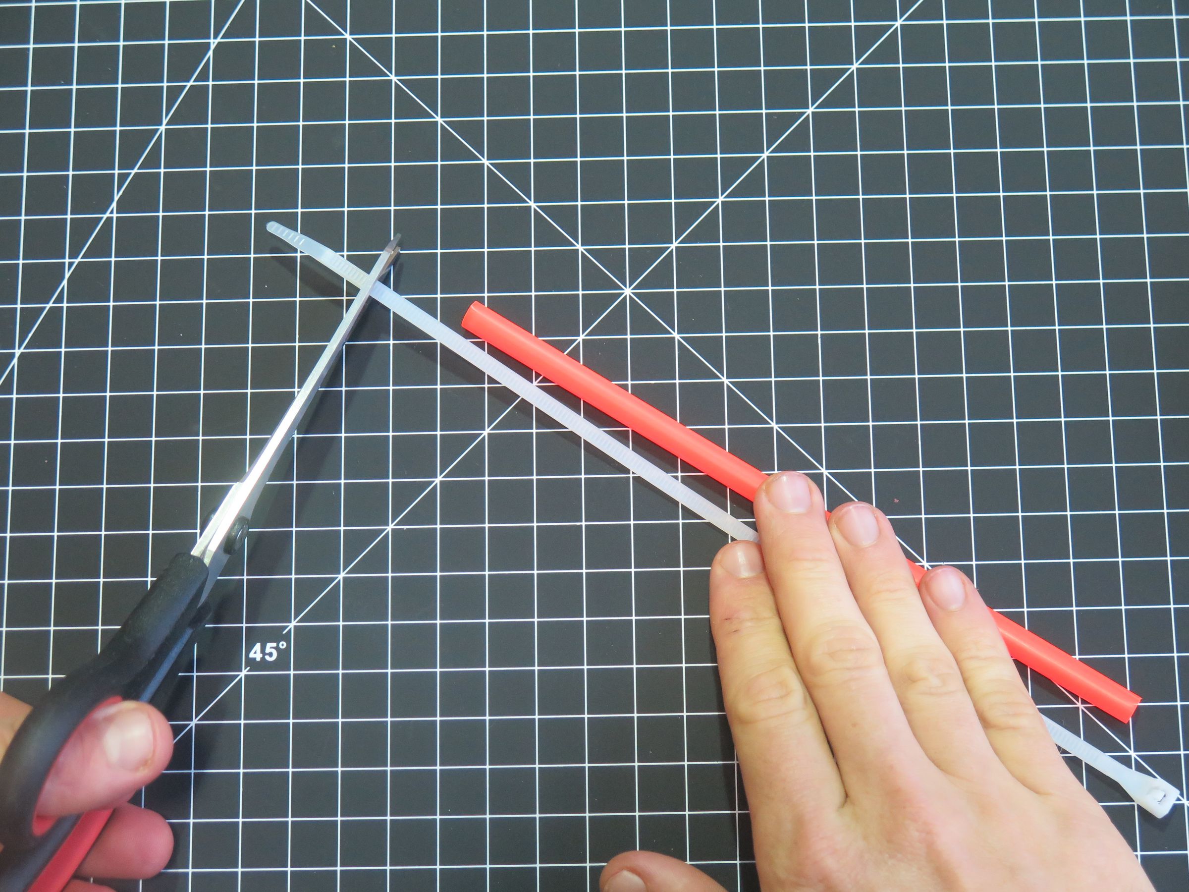 De gewrichten knippen. Vouw het rietje plat en knip er een driehoekig stukje uit: als je het weer openvouwt, ontstaat een ruitvormig gaatje. Herhaal dit een stukje verderop in het rietje, steeds in dezelfde lijn, zodat er meerdere buigpunten (gewrichten) op een rij ontstaan.