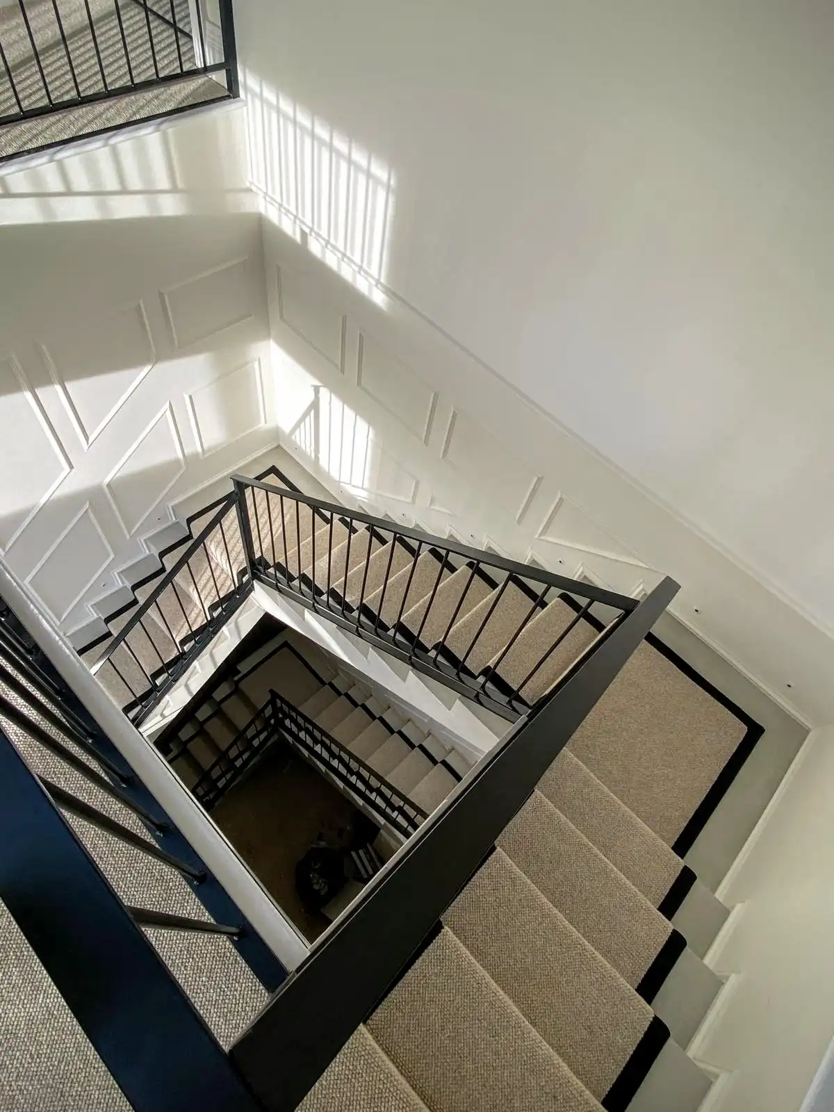 A large lit stairwell with taped carpet spiralling down