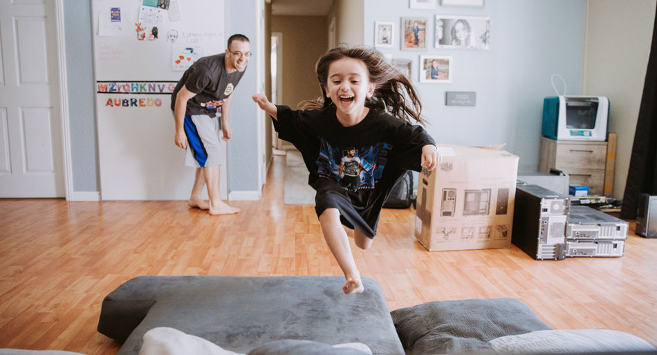 Glad jente løper og hopper opp i sofa