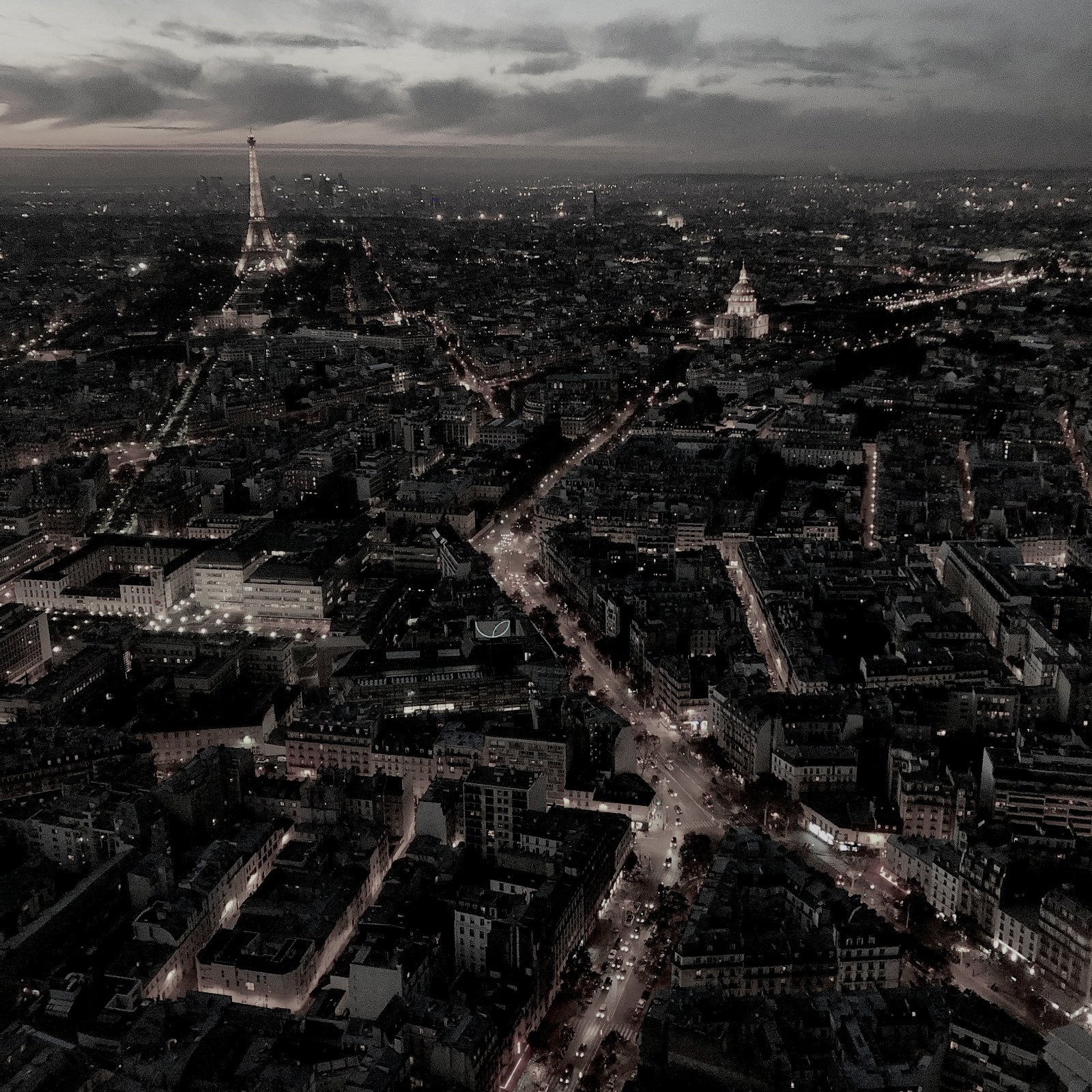 Aerial view of Paris at dusk with the Eiffel Tower lit on the skyline