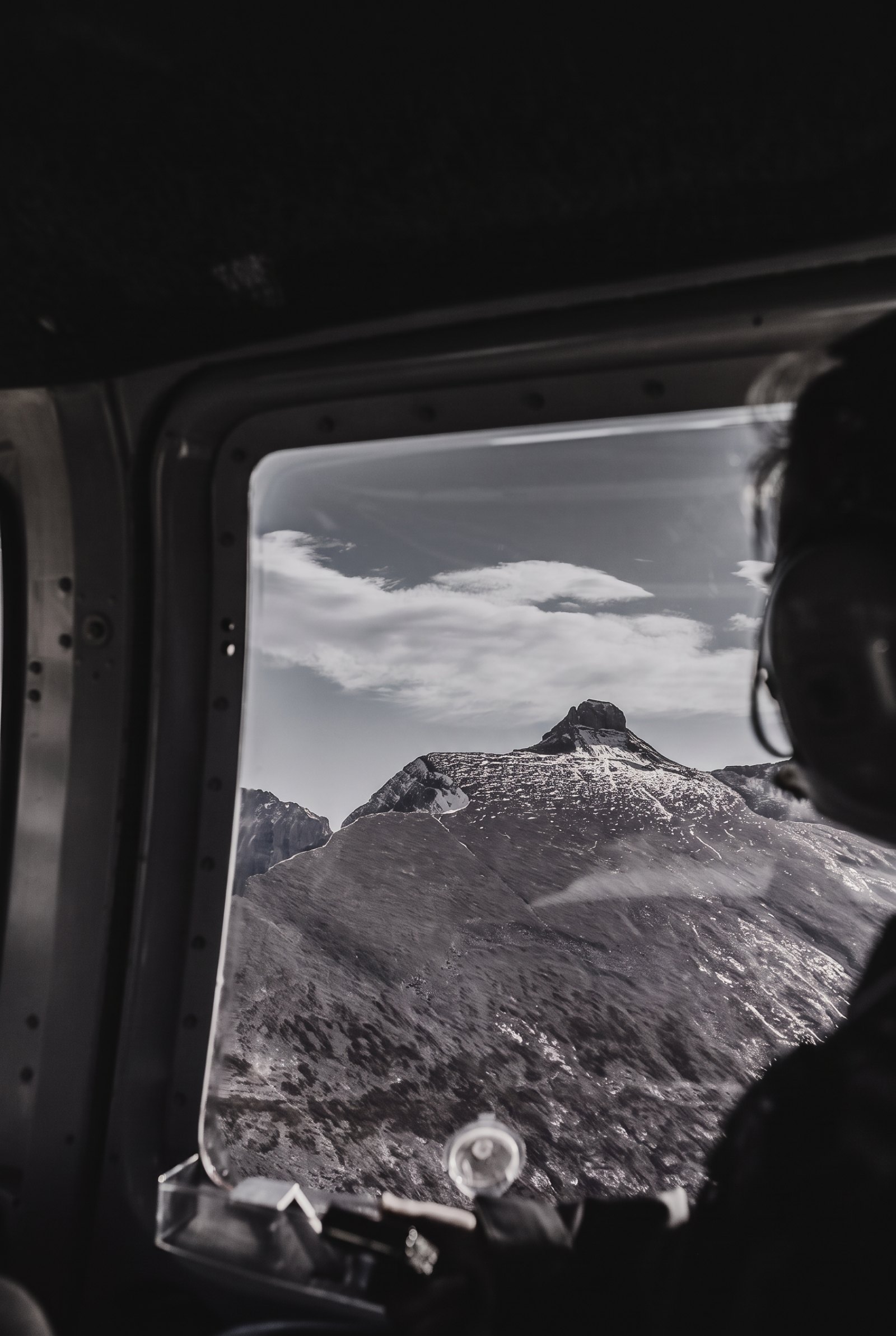 Atmospheric black-and-white photograph of a Highland glen at dusk with a stalking party or a stag silhouetted on a ridge