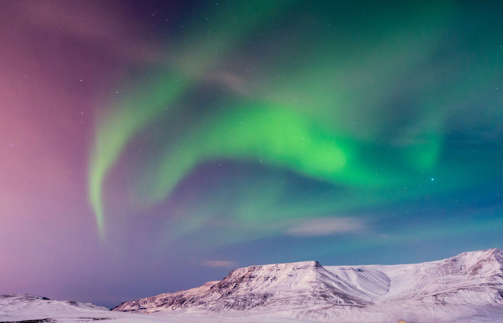 The aurora over snow-covered mountains at night