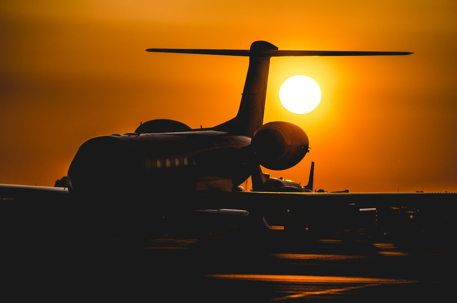 Business jet silhouetted against an orange sunset