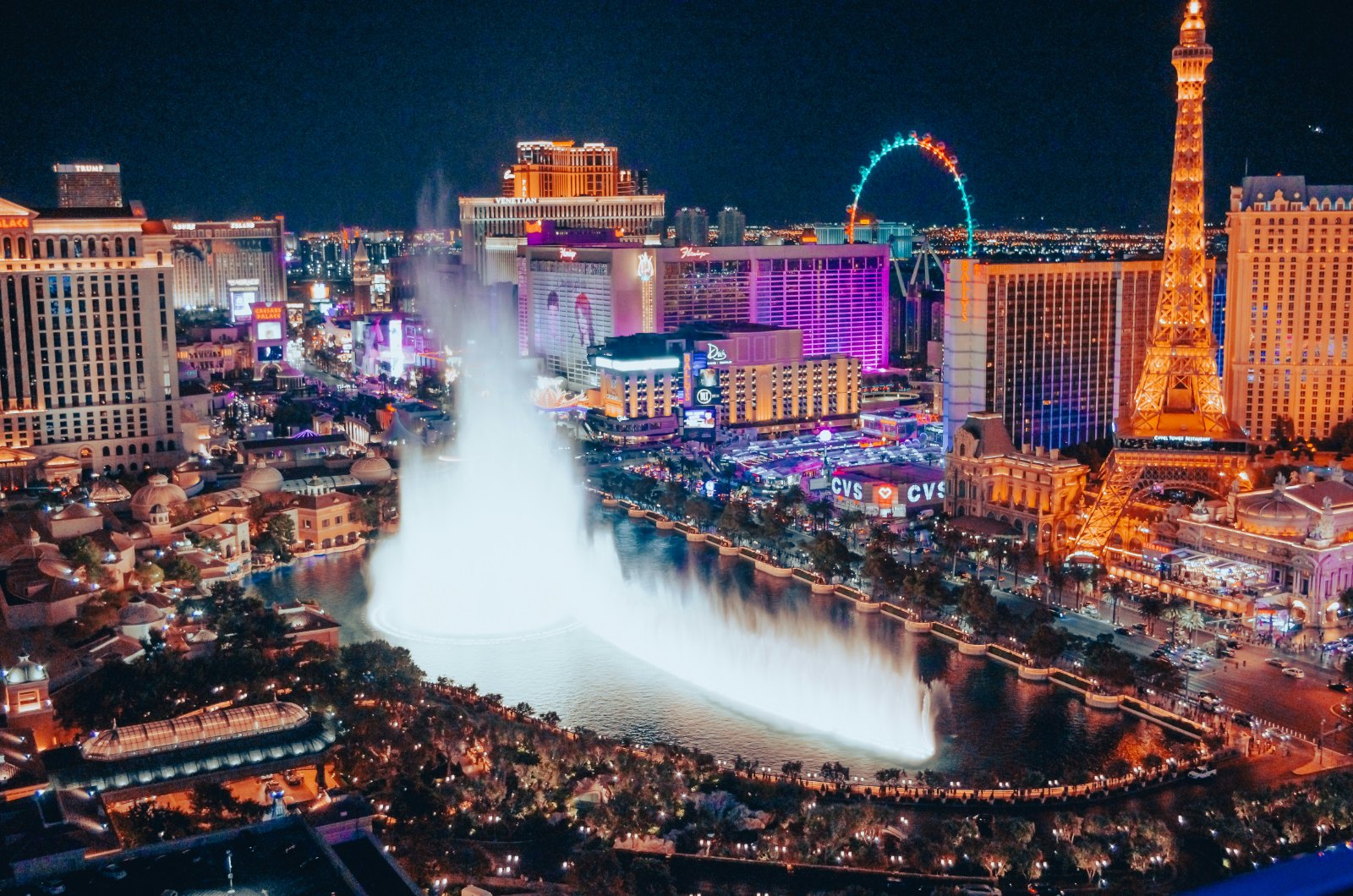 Black-and-white long-exposure view of the Las Vegas Strip at night from a distance, light trails along the boulevard sug