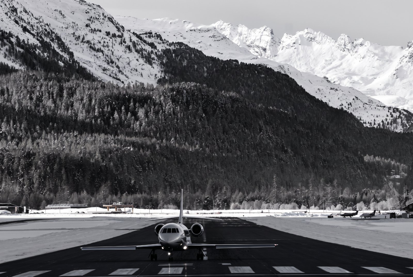 Black-and-white wide landscape of the Engadin valley at Samedan, the runway running along the valley floor beneath high