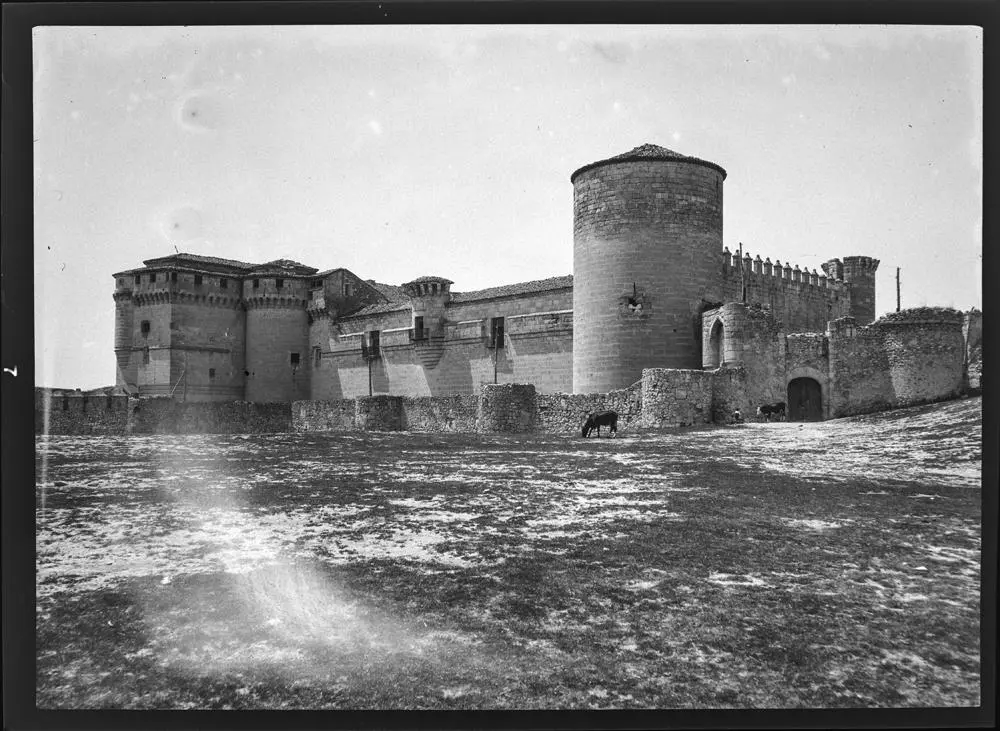 Castillo de Cuéllar (Hof) [Patio del castillo con burro pastando. Destacan la torreo del Homenaje, de forma cilíndrica, y el muro de piedra].