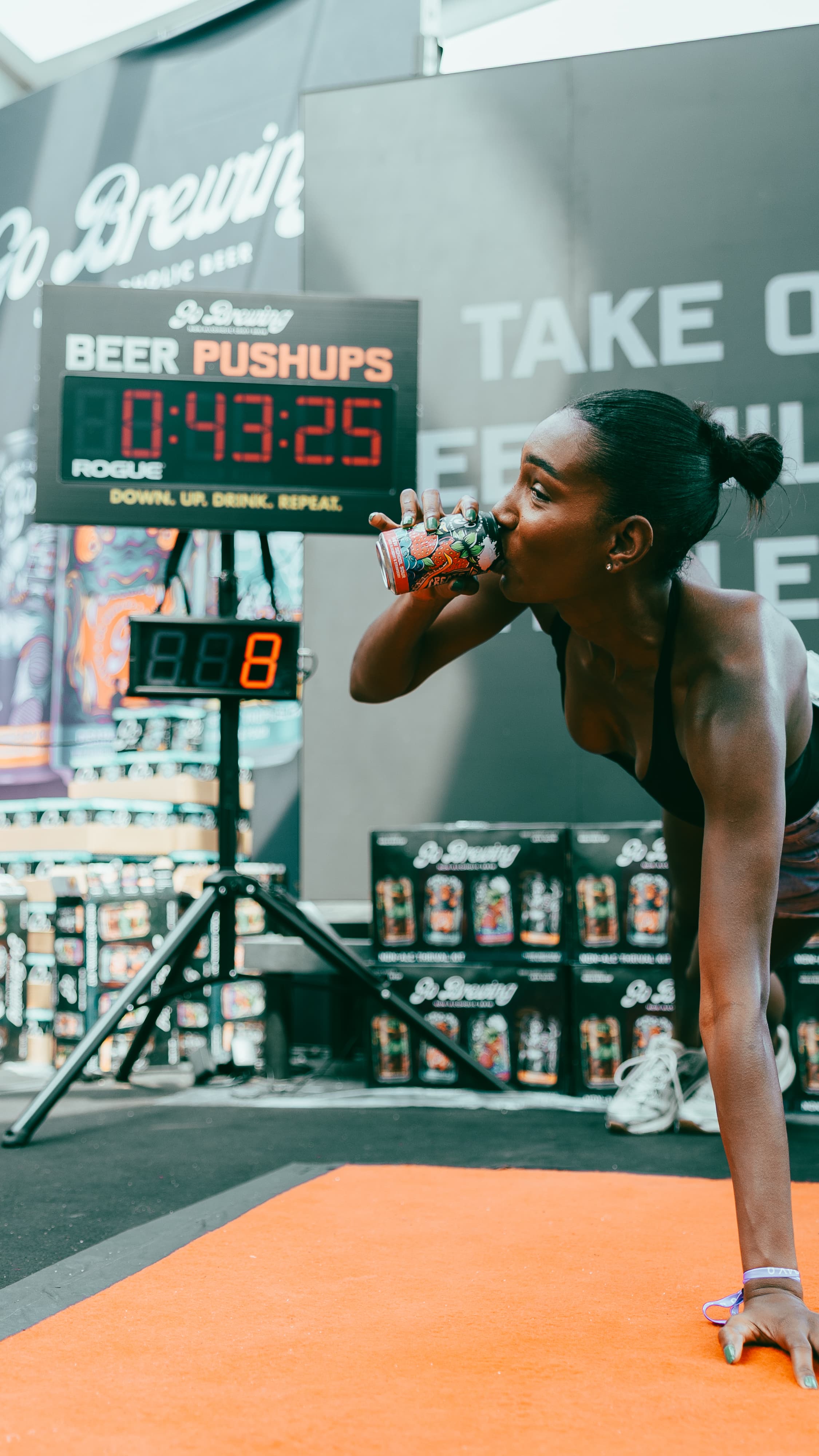 Athlete mid-rep at the Go Brewing push-up challenge booth, scoreboard behind her
