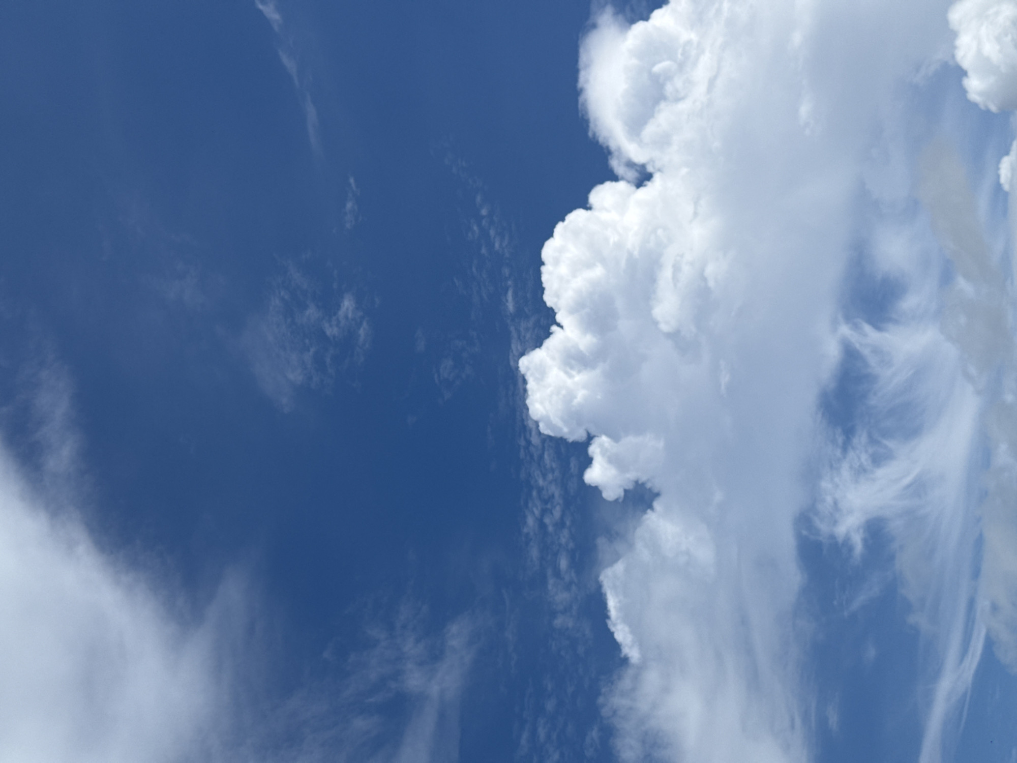 A bright blue sky is visible with scattered white clouds. The clouds vary in density, with some appearing wispy and others more voluminous and puffy. The overall impression is of a clear day with some cloud formations. The image does not depict any identifiable landmarks or features of Karon, Thailand. There are no people, subjects, objects, or actions visible in the image.