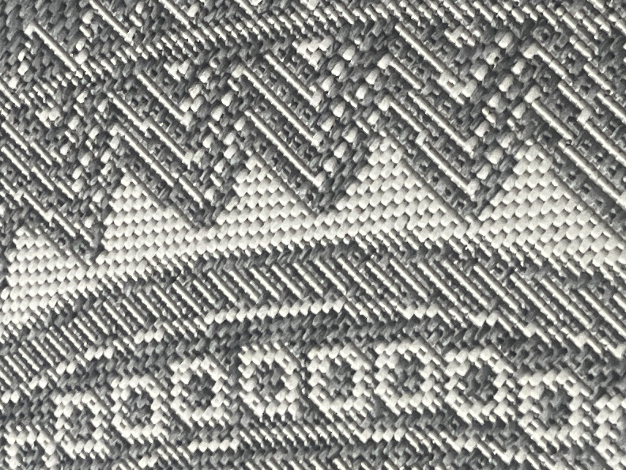 The image displays a close-up, textured view of a woven fabric with a geometric pattern in shades of grey and white. The weave creates a repeating diamond and chevron design. There are no people, animals, or discernible objects that would indicate a specific location within the city of Rybnitsa, Moldova. The focus is entirely on the textile's texture and pattern.